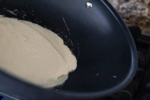 Swirling crepe batter in a nonstick skillet.