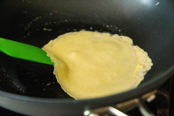 Crepe being flipped in a pan.