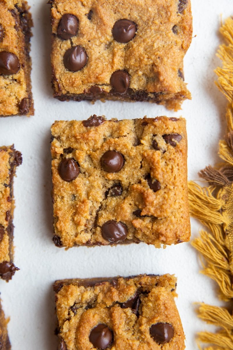 Squares of pumpkin blondies on a white background with a gold napkin.