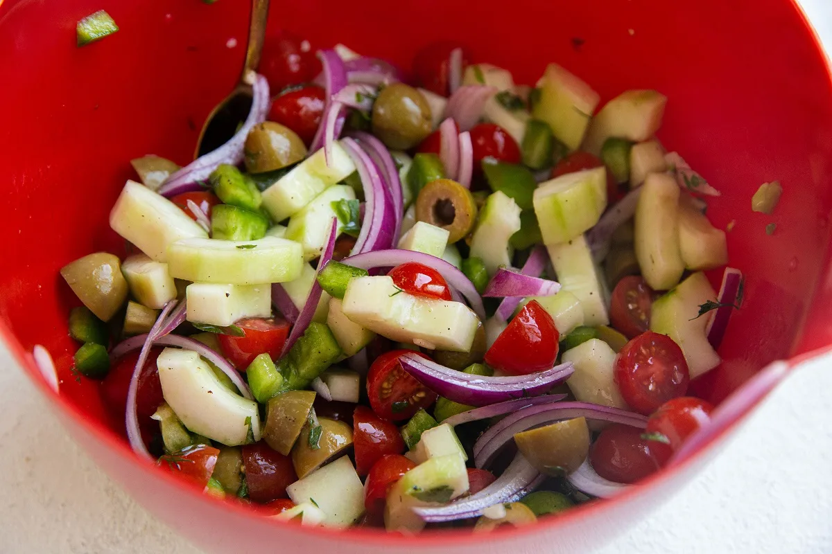 Finished fresh Greek salad in a mixing bowl.