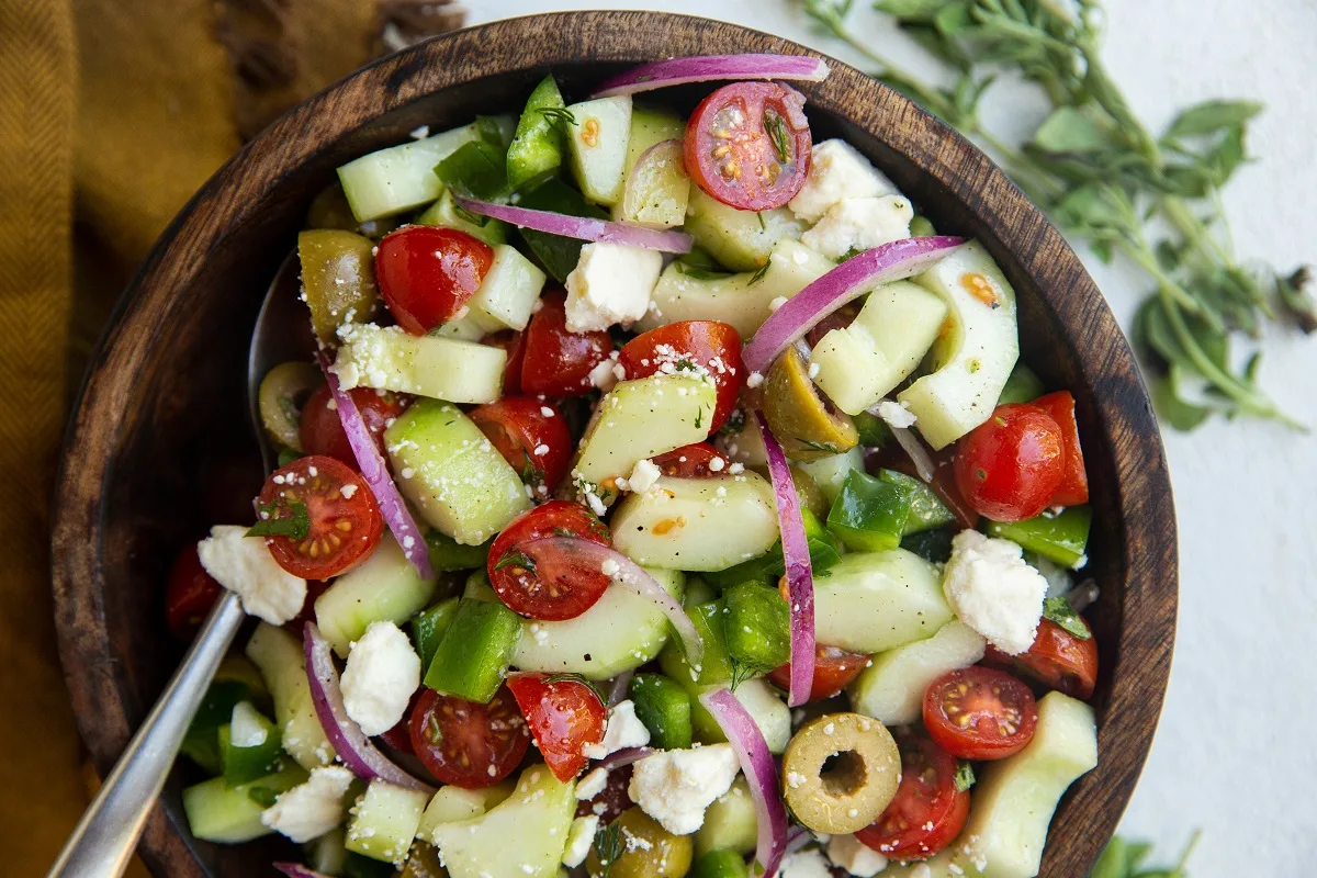 Horizontal photo of authentic Greek salad in a wooden bowl.
