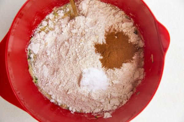 Mixing bowl with wet ingredients, oat flour on top with cinnamon and salt