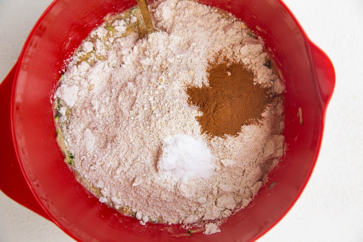 Mixing bowl with wet ingredients, oat flour on top with cinnamon and salt