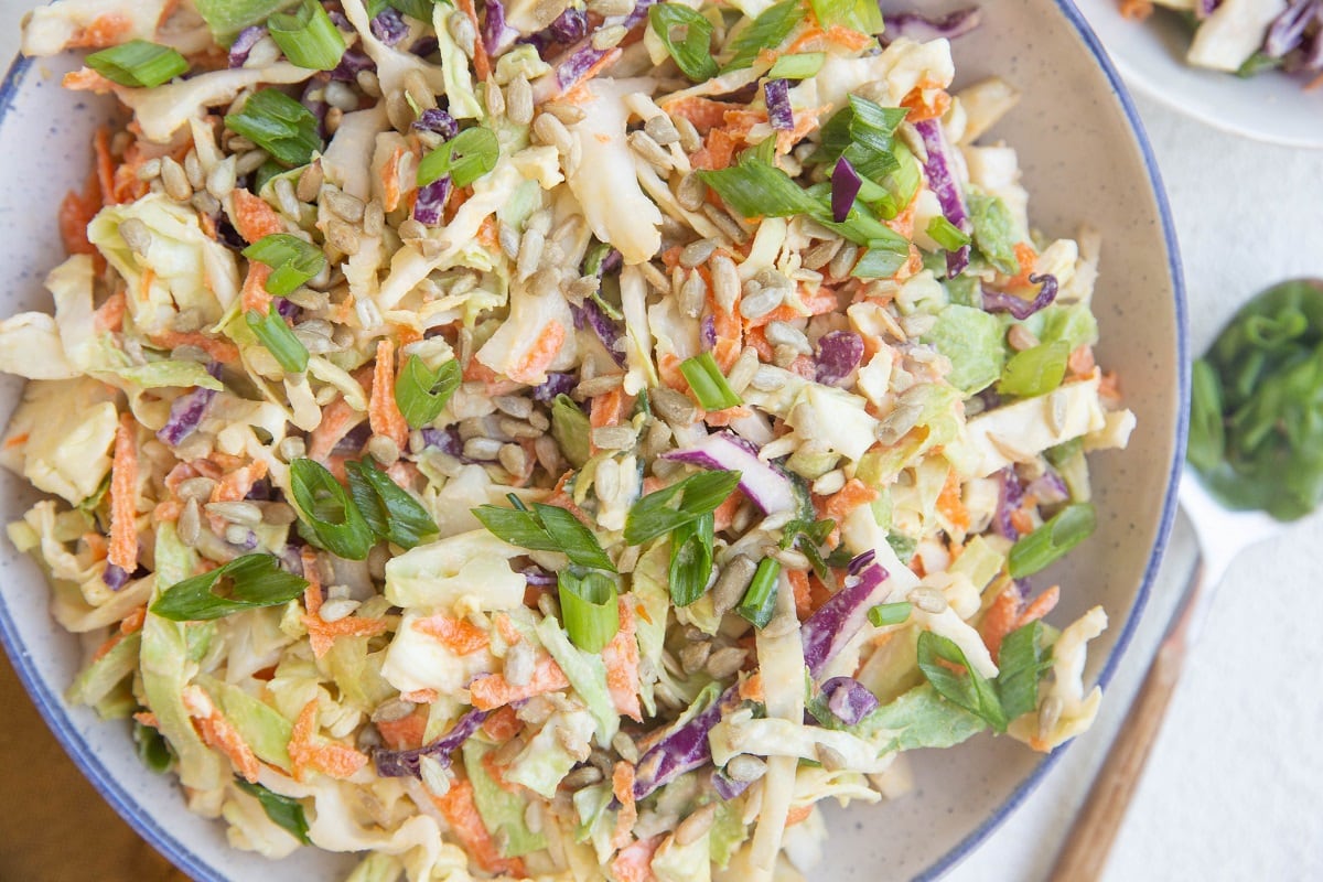 horizontal photo of a blue-rimmed bowl of healthy coleslaw