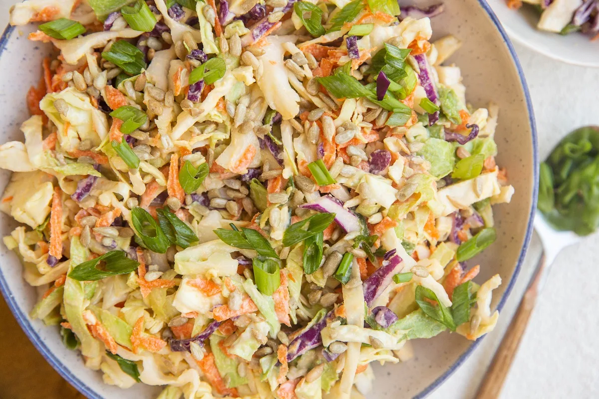 horizontal photo of a blue-rimmed bowl of healthy coleslaw