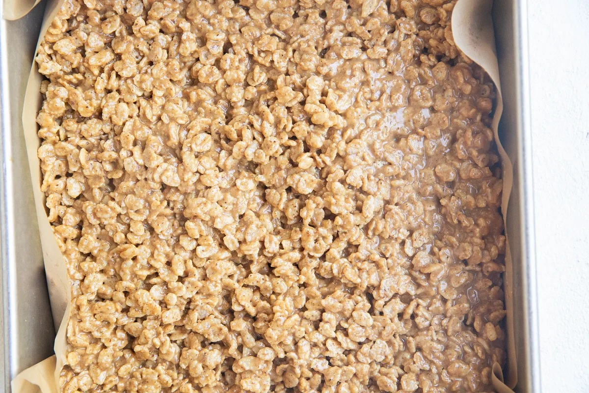 Rice Krispy treats mixture in a baking pan lined with parchment paper