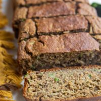 Loaf of zucchini banana bread on a white backdrop in slices.