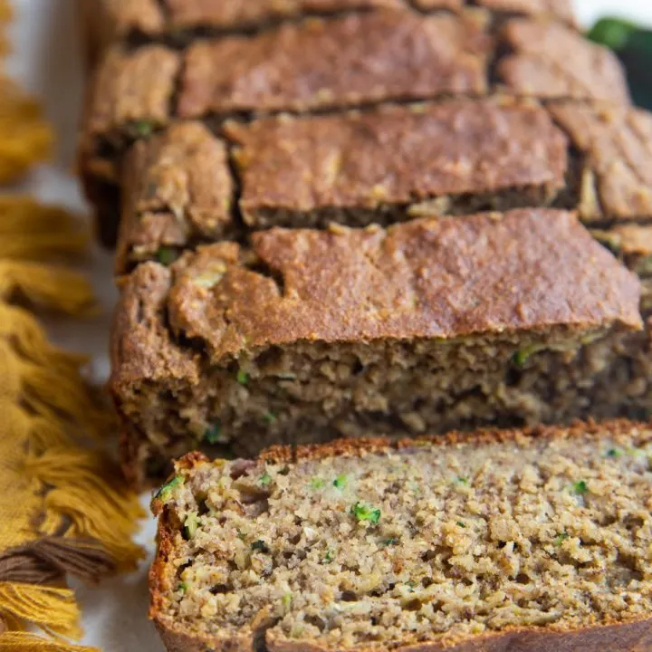 Loaf of zucchini banana bread on a white backdrop in slices.