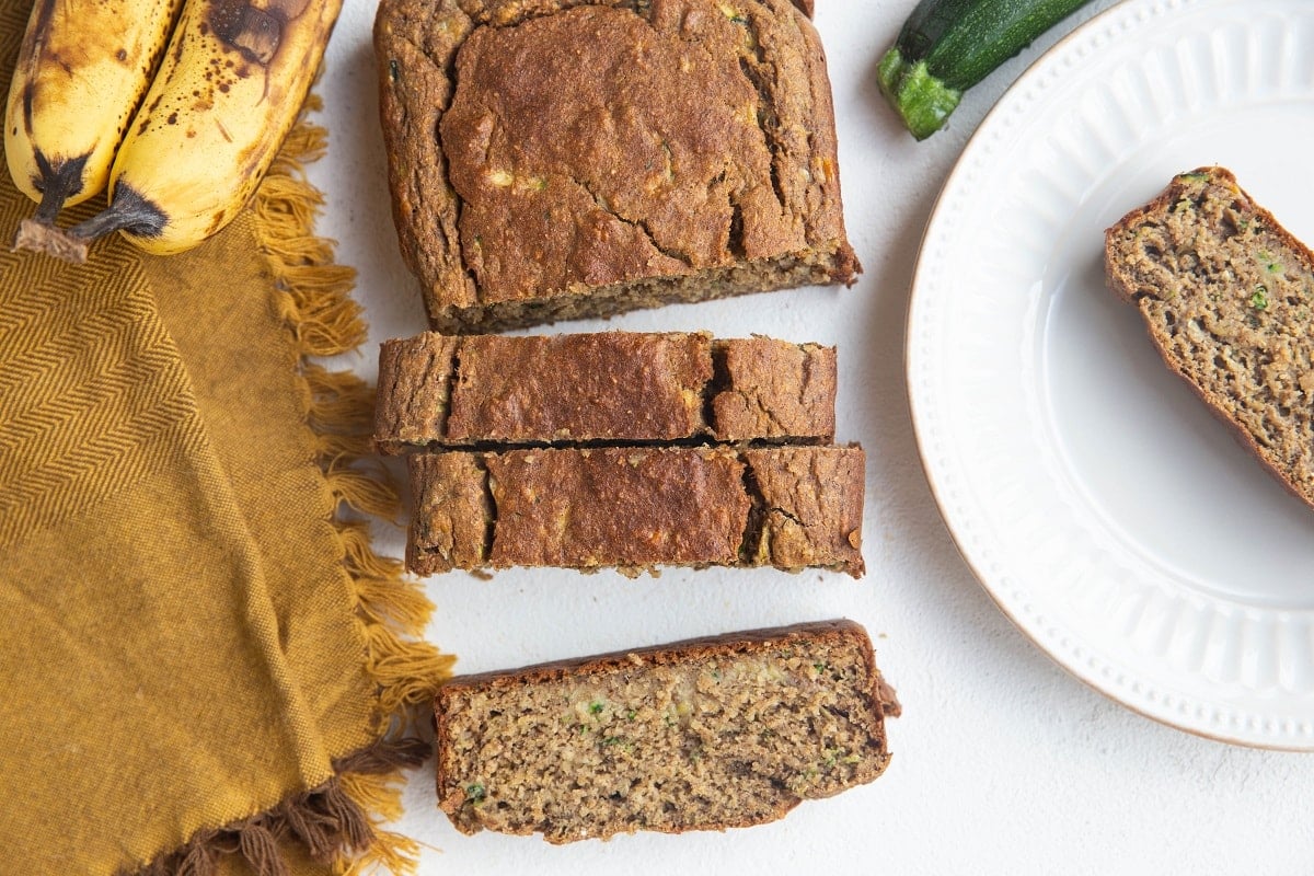 Sliced loaf of zuchini bread with a slice of zucchini bread on a plate