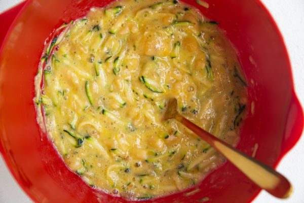 Grated zucchini, ripe bananas and eggs mixed in a mixing bowl.