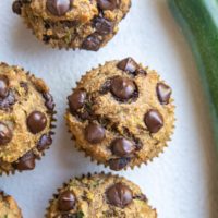 Top down photo of healthy banana zucchini muffins on a white backdrop.