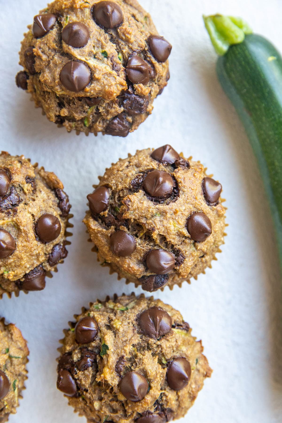 Top down photo of healthy banana zucchini muffins on a white backdrop.
