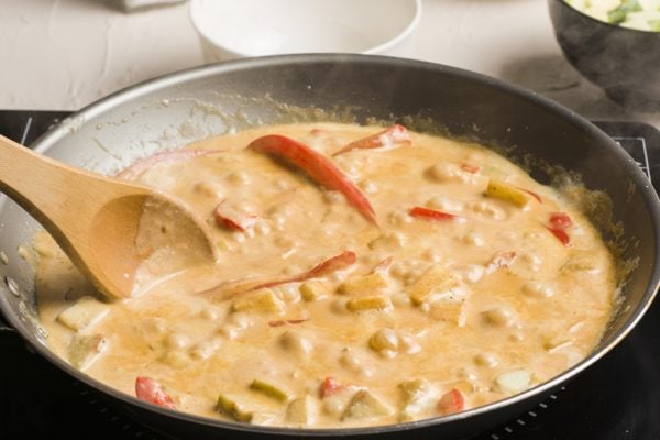 Creamy red curry sauce in a skillet with vegetables
