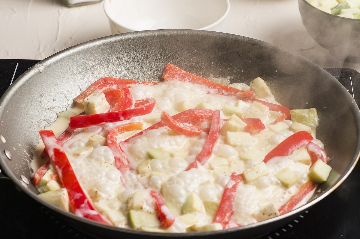 Some of the vegetables cooking in a skillet in coconut milk