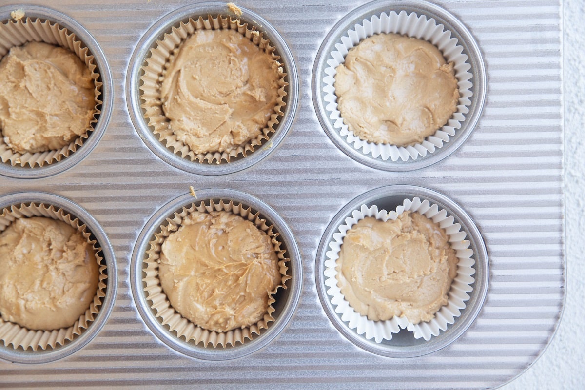 Peanut butter layer on top of chocolate layer in muffin papers in a cupcake tin for pb cups