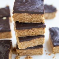 Stack of peanut butter oatmeal bars with a layer of chocoalte on top.