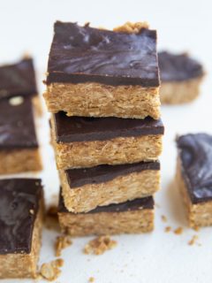 Stack of peanut butter oatmeal bars with a layer of chocoalte on top.