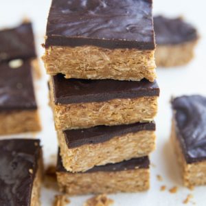 Stack of peanut butter oatmeal bars with a layer of chocoalte on top.