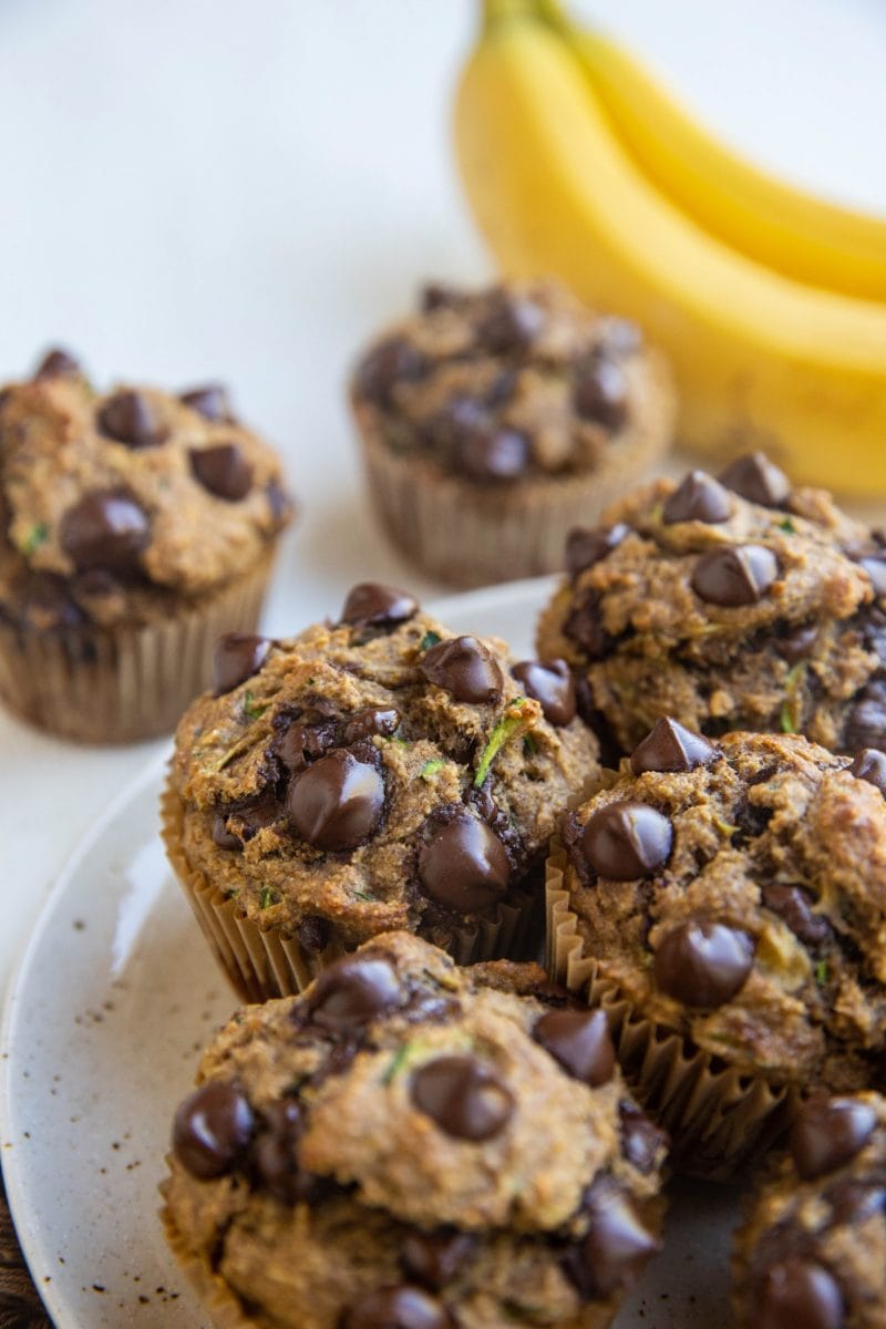 Plate of healthy banana zucchini muffins with bananas in the background.