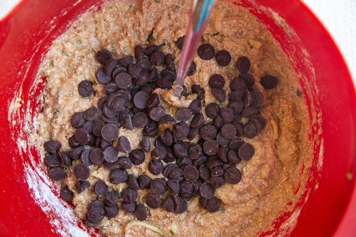 Muffin batter in a mixing bowl with chocolate chips on top.