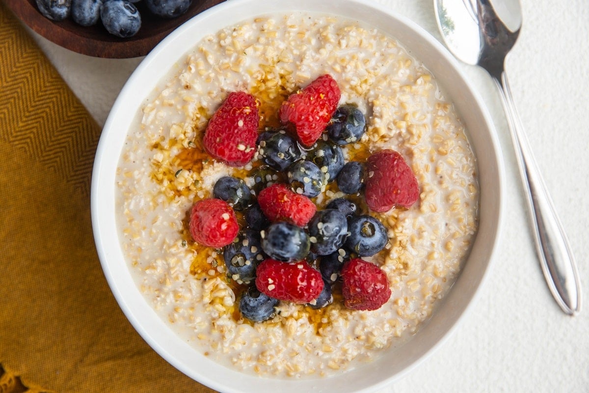 horizontal photo of white bowl of oatmeal with fresh fruit on top.