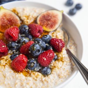 close up image of steel cut oatmeal in a bowl with fresh fruit and a spoon.
