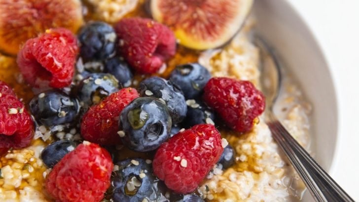 close up image of steel cut oatmeal in a bowl with fresh fruit and a spoon.