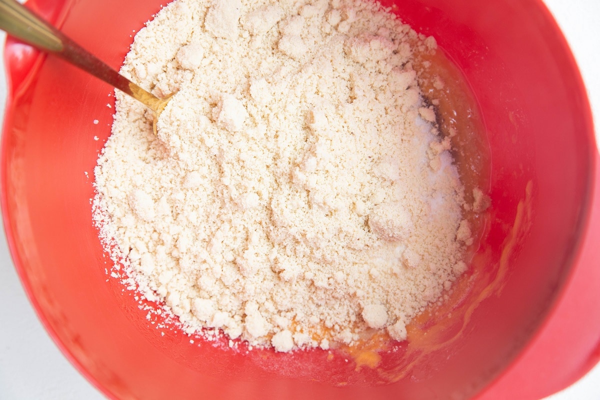 Mixing bowl with whisked wet ingredients and dry ingredients on top, ready to be mixed in.