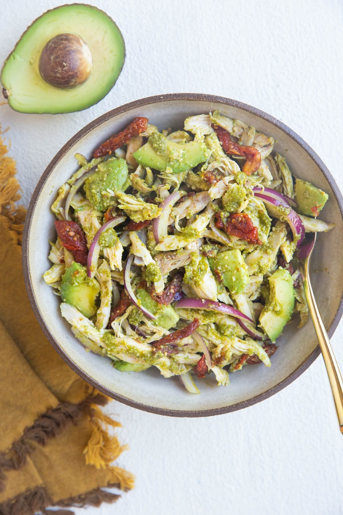 large bowl of chicken salad with avocado and napkin to the side.