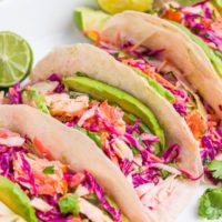 Four salmon tacos on a serving platter.