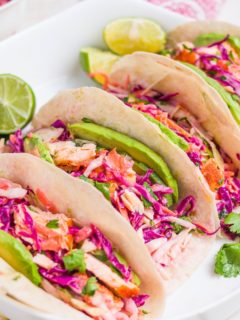 Four salmon tacos on a serving platter.