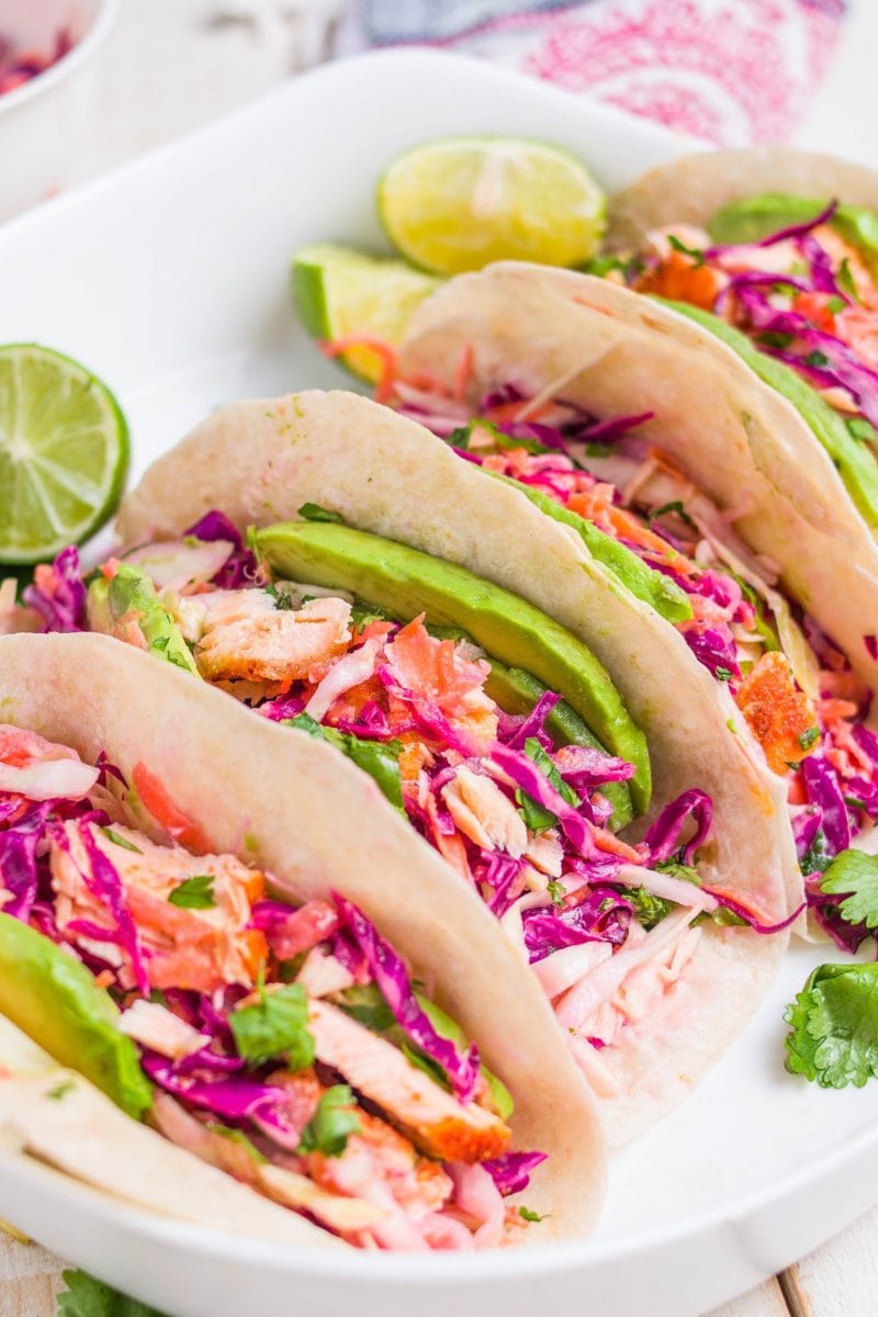 Four salmon tacos on a serving platter.