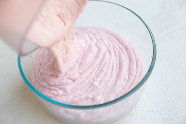 Pouring strawberry mixture into a freezer container to freeze