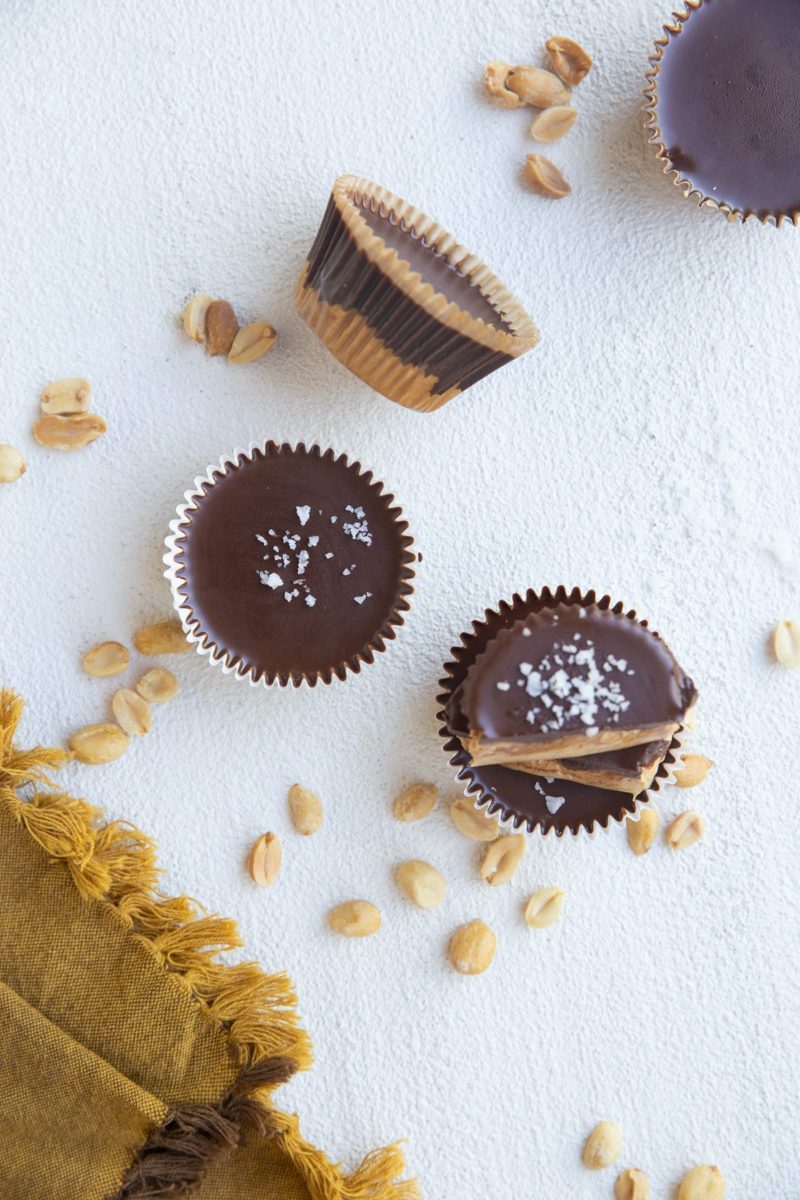 Top down photo of peanut butter cups with peanuts scattered all around.