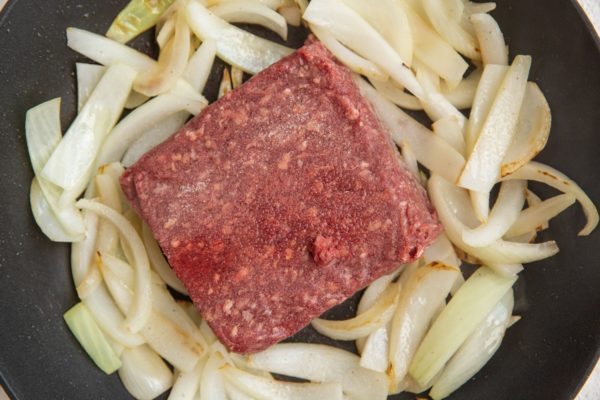 onions sautéing and beef browning in a skillet