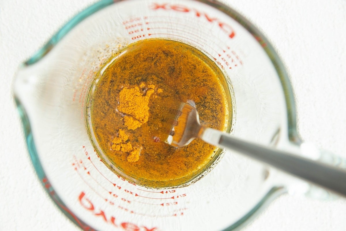 Seasonings and oil for curry cauliflower in a measuring cup.