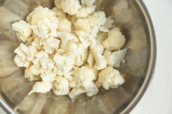 Raw chopped cauliflower in a mixing bowl.