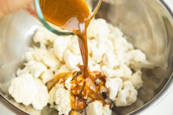 Pouring the oil and seasonings over the cauliflower.