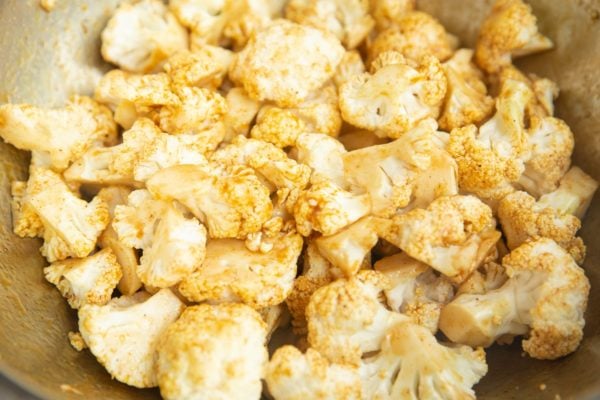 Seasoned cauliflower in a mixing bowl, ready to be air fried
