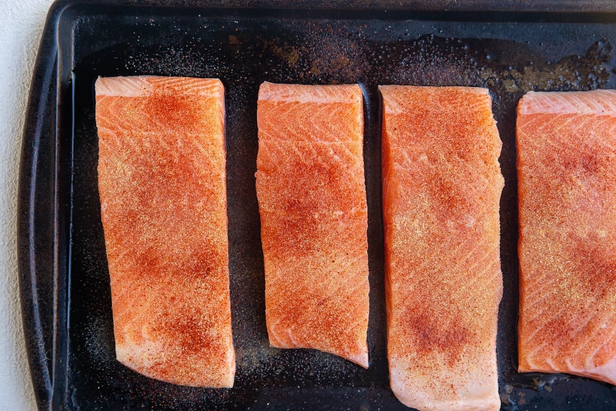 Salmon sprinkled with seasonings on a baking sheet.