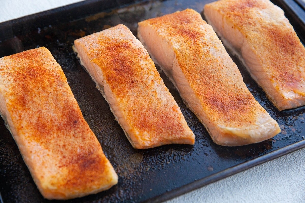 Baked salmon on a baking sheet, ready to be broiled