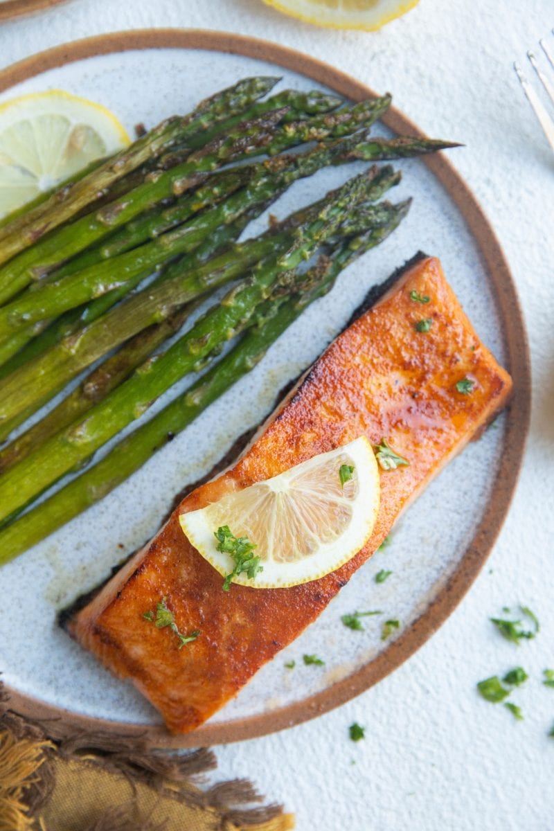 Top down photo of baked salmon and asparagus on a plate.