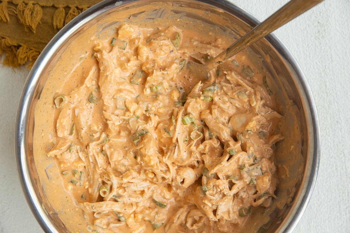 Ingredients for buffalo chicken dip stirred up in a bowl, ready to go into the oven.