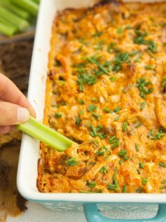 Hand scooping buffalo chicken dip onto a celery stick.