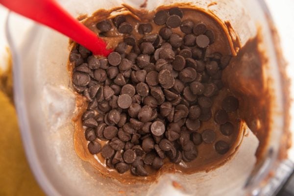 Chocolate banana bread batter with chocolate chips on top, ready to be stirred in