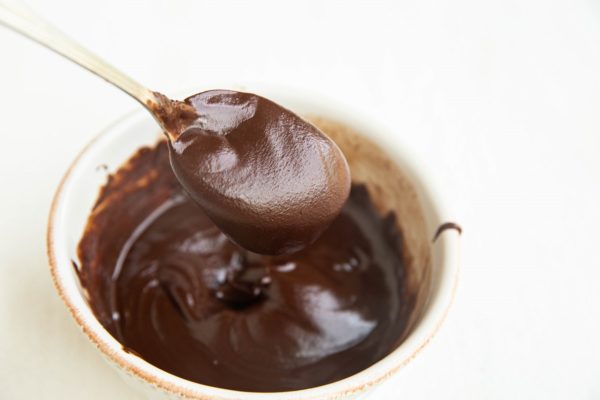 Melted chocolate chips in a bowl with a spoon showing a scoop.