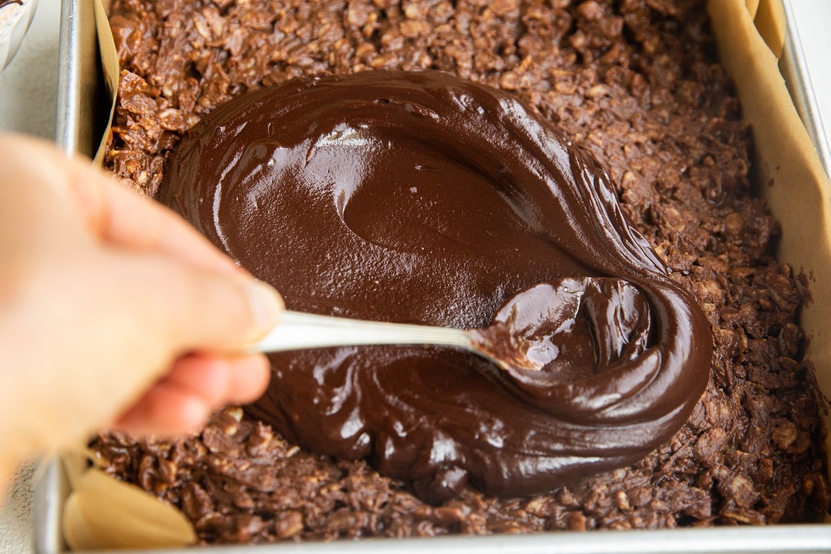 Spreading melted chocolate over chocolate rice krispies