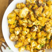 Air Fryer Curry Cauliflower Recipe in a white bowl, sprinkled with parsley, ready to serve.