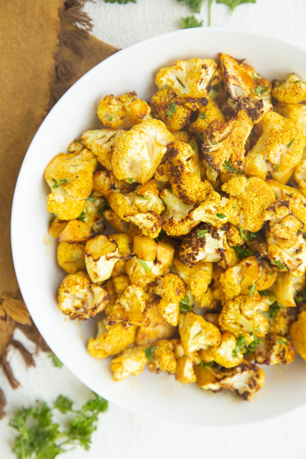 Air Fryer Curry Cauliflower Recipe in a white bowl, sprinkled with parsley, ready to serve.