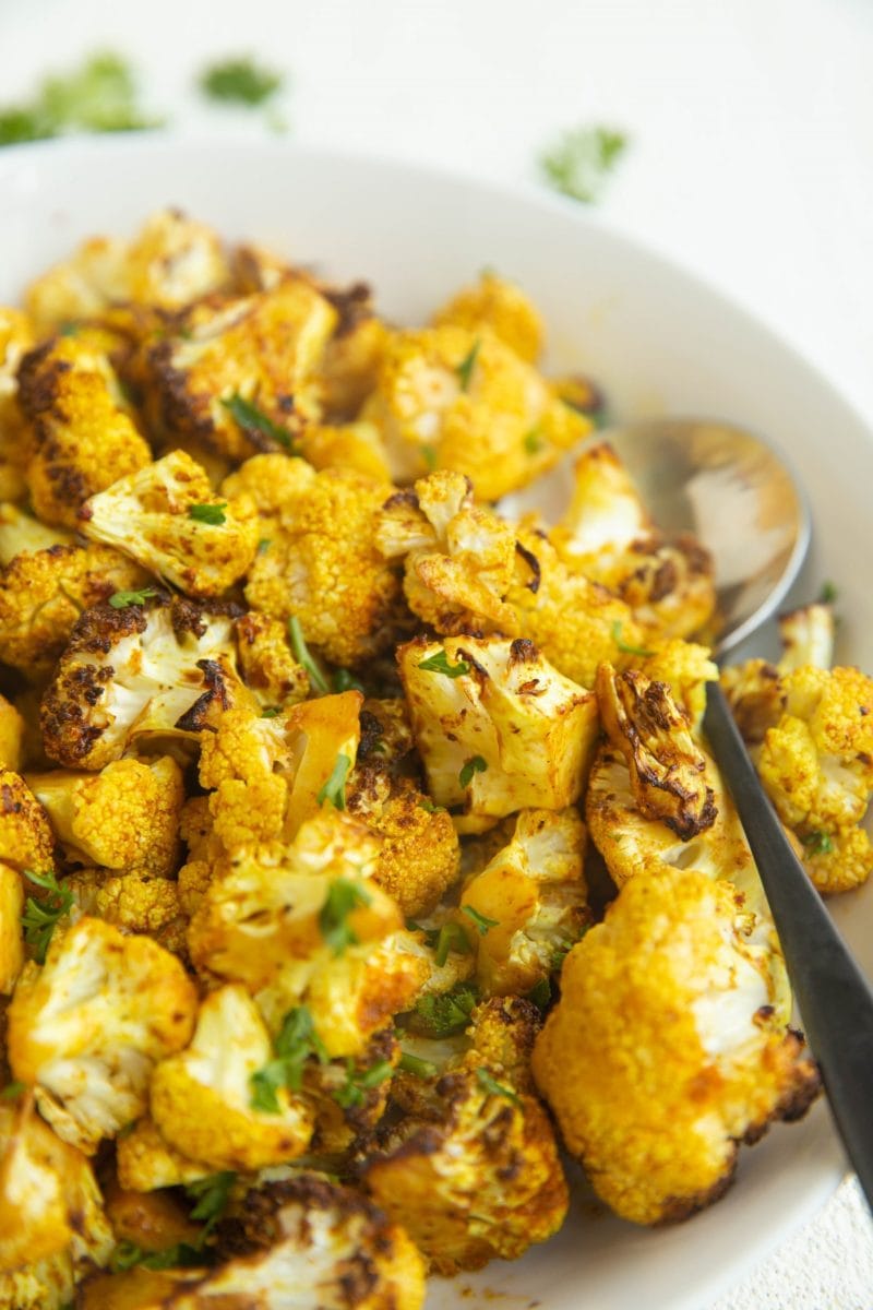 Close up shot of curried cauliflower in a white bowl.